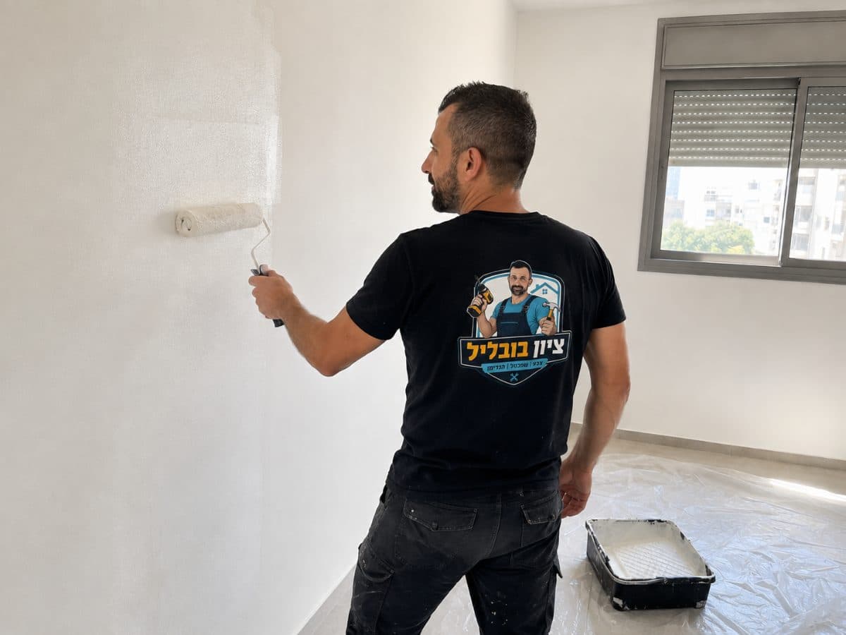 רולר צבע נטען בצבע לבן במגש, ליד קיר בצביעה