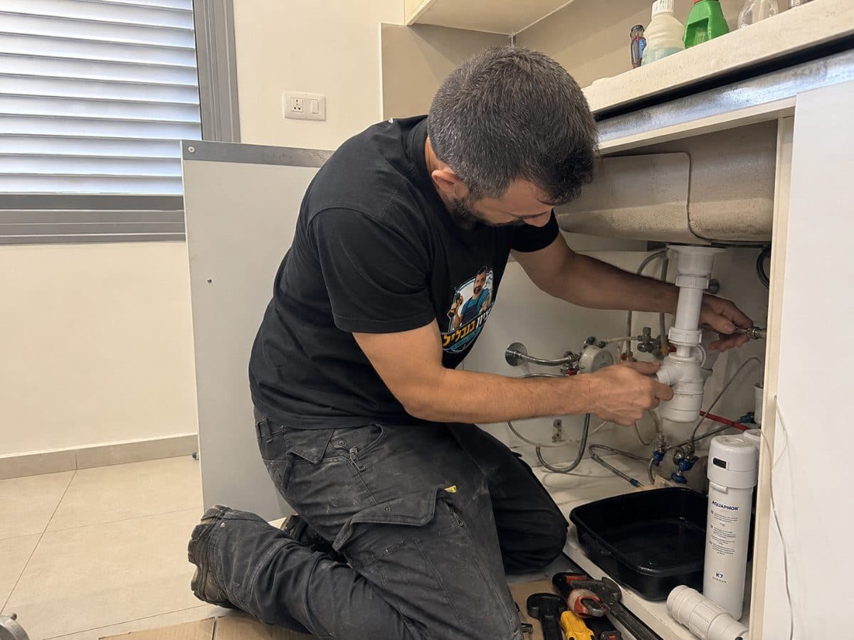 עבודה על סיפון וחיבורי מים בתוך ארון מתחת לכיור